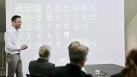 Software-Training, wo ein Berater vorne vor einer Leinwand steht.