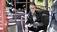 Mann erfasst Arbeitszeit mobil im Bus auf seinem Tablet.