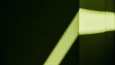 Eine grüne Wand von der nur ein Teil durch Lichteinfall beleuchtet ist.