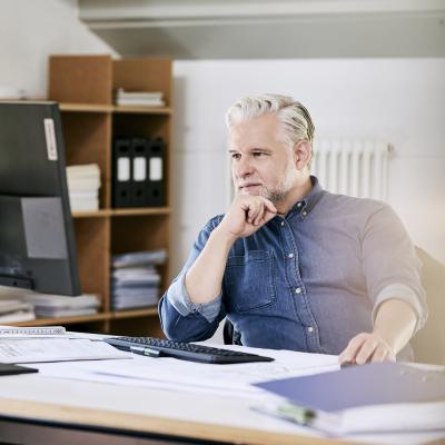 Ein Mann (Ingenieur) sitzt am Schreibtisch und arbeitet.