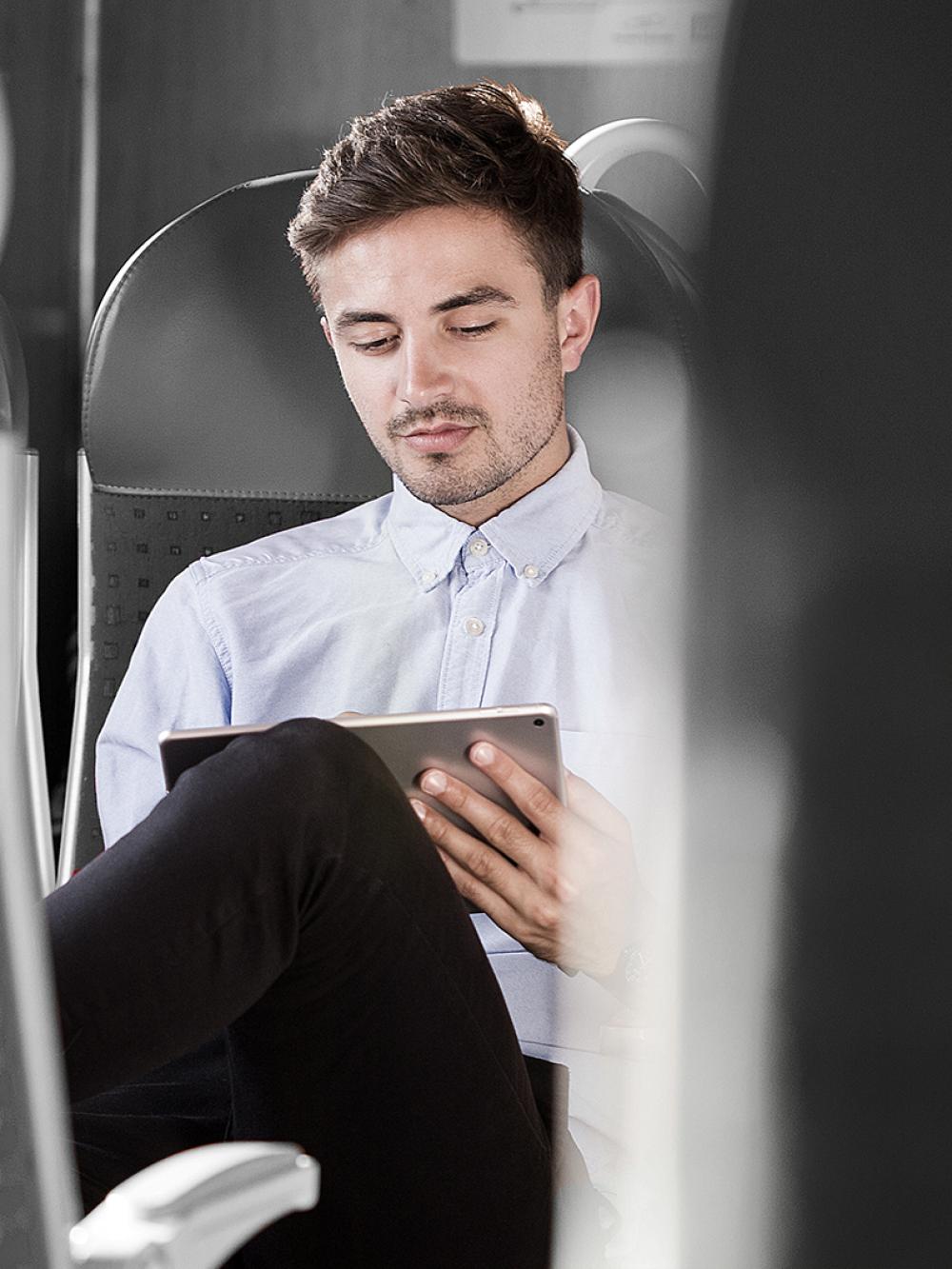 Mann im Zug nutzt mobile Zeiterfassung mit dem Tablet.