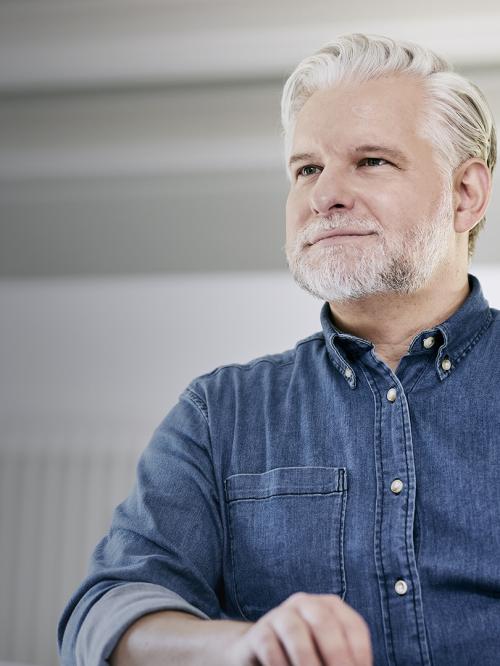 Mann (Ingenieur) arbeitet am Schreibtisch und lächelt.