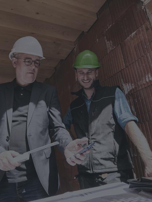 3 Männer auf der Baustelle schauen auf ein Smartphone.