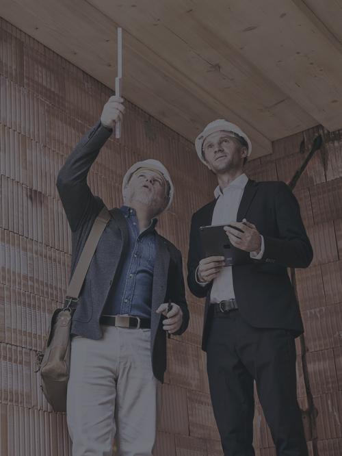 Zwei Männer besichtigen die Baustelle mit Tablet und Meterstab