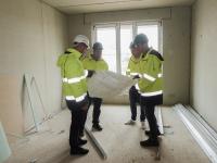 4 Mitarbeiter auf einer Baustelle schauen auf einen Plan.