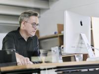 Mann arbeitet konzentriert am Computer und schaut sich Auswertungen an.