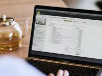 Notebook und daneben steht eine Teekanne.