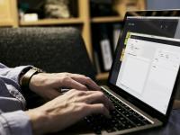 Mann arbeitet zu Hause am Macbook und checkt Emails.