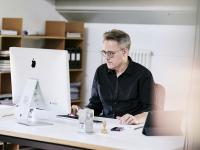 Mann arbeitet konzentriert mit Bildschirm im Büro.