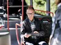 Mann im Bus tippt auf einem iPad