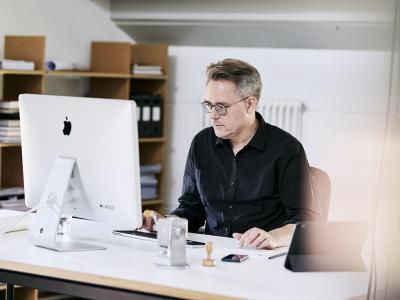Mann arbeitet konzentriert mit Bildschirm im Büro.